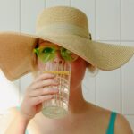 Frau mit Hut trinkt Wasser