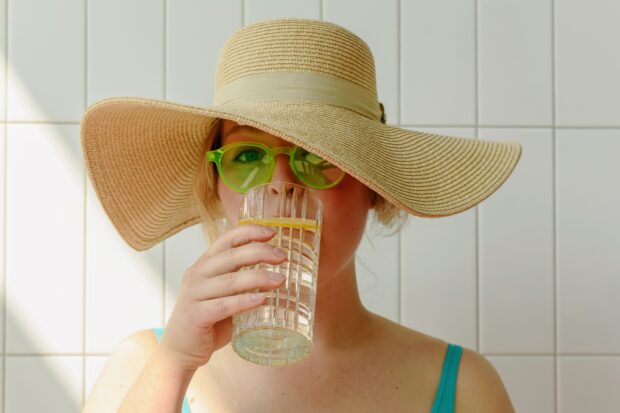 Frau mit Hut trinkt Wasser